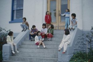 Group of children seated on the front steps, having conversations.
