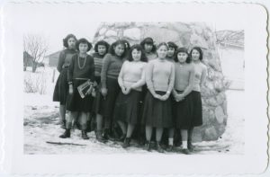 Group of youth standing in front of a large cairn in winter.