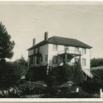 Port Simpson Residential School building, three-storeys with a large veranda entrance, white fence, and large conifers to the left