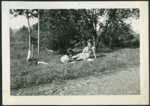 Two children laying in grass reading books by the roadside