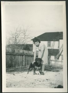 Child holding back standing puppy with Port Simpson Residential building in the background