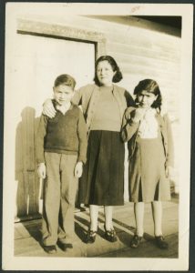 Staff with arms around two children standing on a veranda