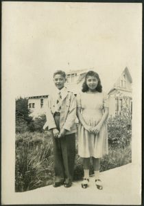 Two children standing on boardwalk with building in the background