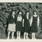 Four youth standing in front of a tall hedge