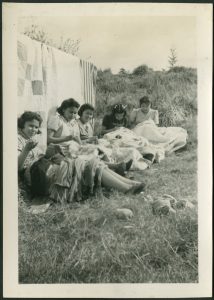 Youth sitting by clothesline of drying laundry mending garments