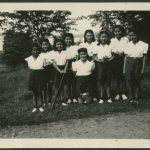 Group of youth with softball, bat, and trophy, posed in a field