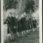 Blurry photo of children leaning on fence wearing jackets and hats