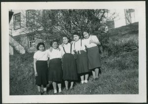 Group youth linked by hands on each others shoulders, on hillside next to Port Simpson Residential School