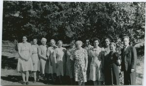 Rev. R. T. Chapin and staff of Brandon Residential School standing posed for a photo outdoors.