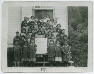 Children and adults standing posed for a photo on some steps with the auxiliary banner at centre.