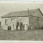 Old school house with three staff members standing in front of it.