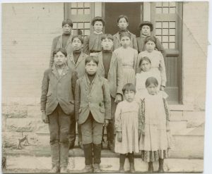 Twelve children standing on steps of institution, caption reads 