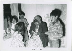 Three children standing around older adult who is holding a craft in hands