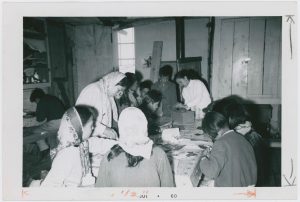 Children standing and sitting around table crafting.